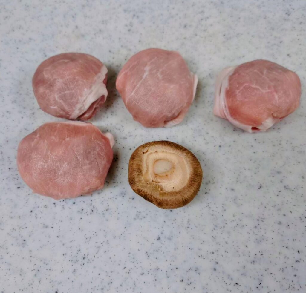 肉厚しいたけを豚肉で包んだ下ごしらえの様子。調理前の丸い肉巻きが並んでいる