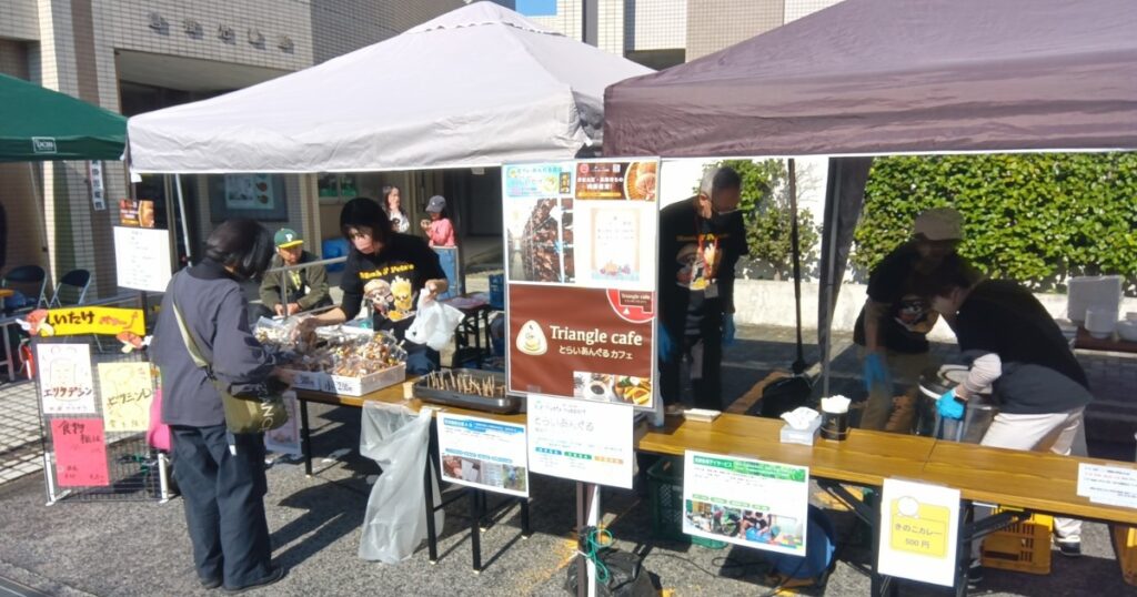 とらいあんぐるカフェのブースで、とらいあんぐる農園の生椎茸や乾燥椎茸、椎茸カレーを販売するスタッフの様子。